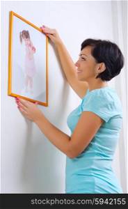 Smiling woman hanging up photo of little girl