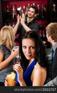 Smiling woman having drink with friends at cocktail bar