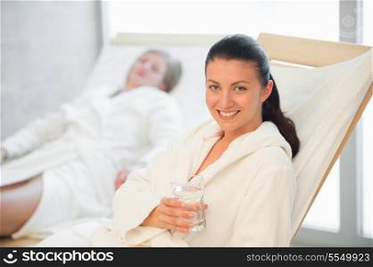 Smiling woman hold glass of water at beauty spa
