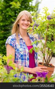 Smiling woman hold tree plant at garden centre shopping