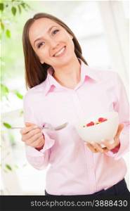 Smiling woman holding a bowl with corn flakes with berries in her hands