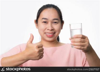 Smiling woman holding a glass of water and thumbs up on white background in studio. Healthy lifestyle