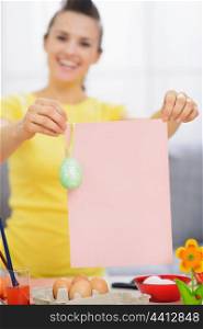 Smiling woman holding blank paper with Easter egg