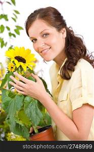 Smiling woman holding flower pot with sunflower on white background