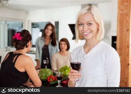 Smiling woman holding glass at party with female friends in background