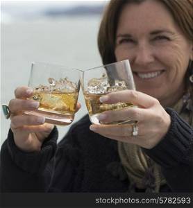 Smiling woman holding glasses of whisky, Lake Argentino, Santa Cruz Province, Patagonia, Argentina