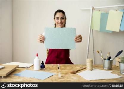 smiling woman holding handmade blue paper