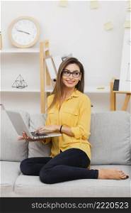 smiling woman holding laptop looking away
