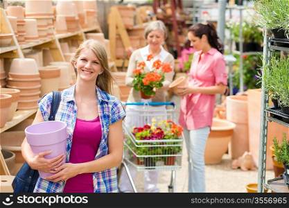 Smiling woman holding purple pot in garden store greenhouse center