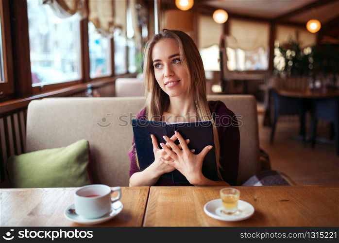 Smiling woman in a restaurant holding menu in hands.