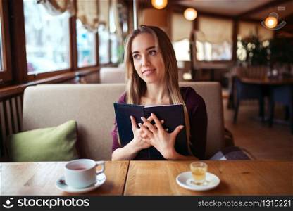 Smiling woman in a restaurant holding menu in hands.