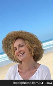 Smiling woman in a straw hat on the beach