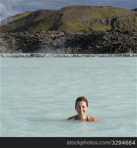 Smiling woman in bathing suit submerged in geothermal mineral pool