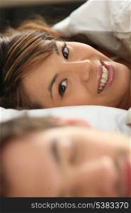 Smiling woman in bed with her partner