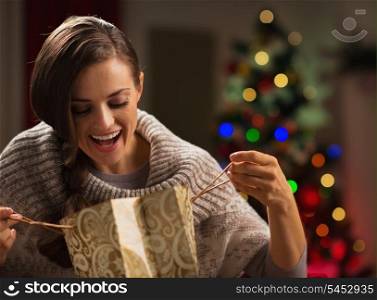Smiling woman in front of Christmas tree looking in shopping bag