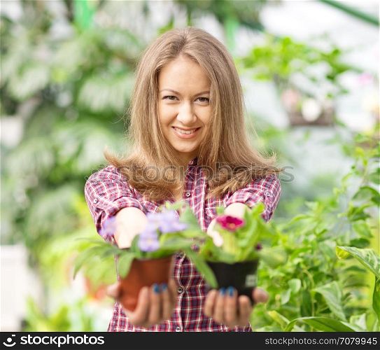 smiling woman in greenhouse with flower pots