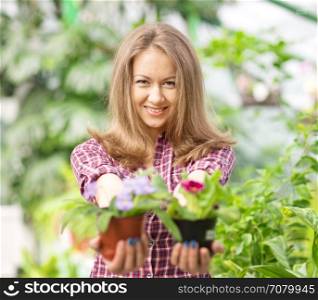 smiling woman in greenhouse with flower pots