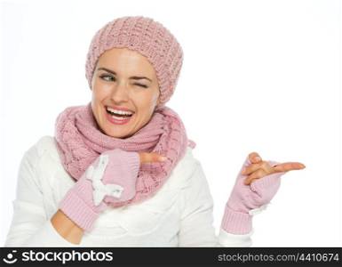 Smiling woman in knit winter clothes pointing on copy space and winking