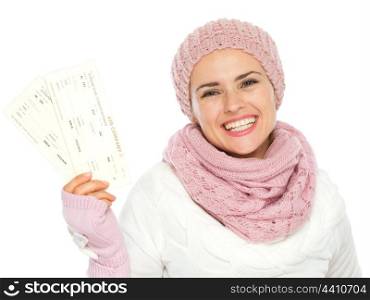 Smiling woman in knit winter clothing holding air tickets
