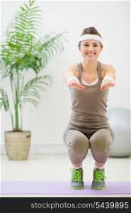 Smiling woman in sports wear squatting
