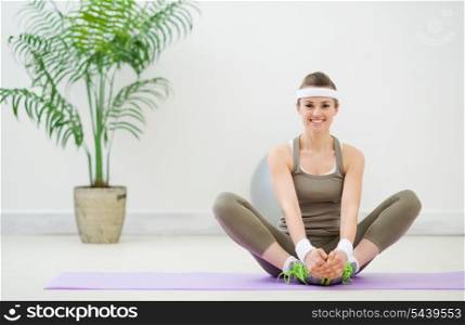 Smiling woman in sportswear making stretching exercises