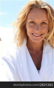 Smiling woman in toweling robe outdoors