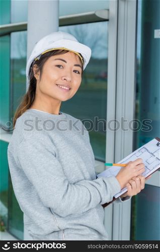 smiling woman in white helmet with clipboard
