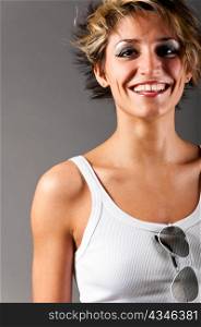 smiling woman in white tank top and jeans on gray background