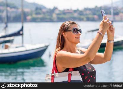 smiling woman is taking a selfie near the lake