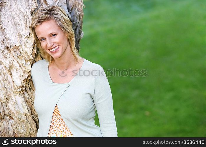 Smiling Woman Leaning Against Tree