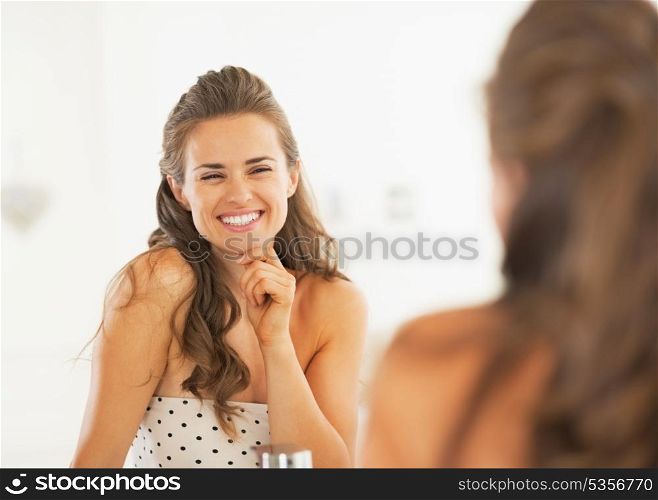 Smiling woman looking in mirror in bathroom
