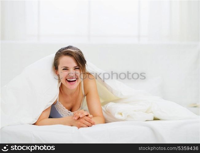 Smiling woman looking out from blanket