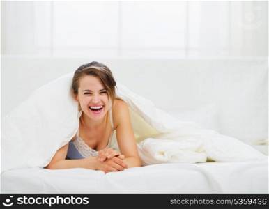 Smiling woman looking out from blanket