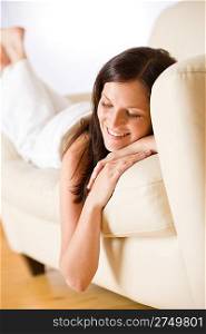 Smiling woman lying down on sofa in lounge