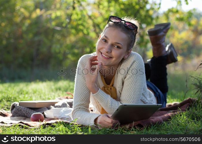 smiling woman lying on bedding with ipad during fun outdoors