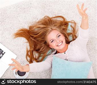 smiling woman lying on carpet with pillow and coffee