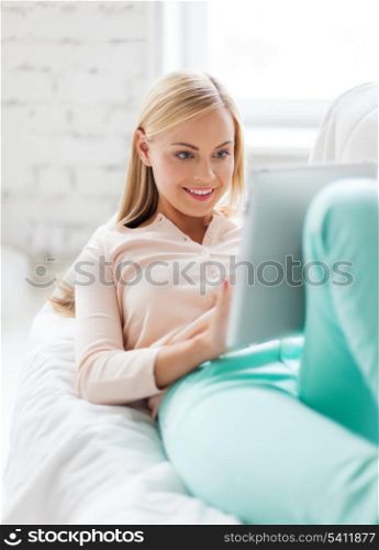 smiling woman lying on the couch with tablet pc