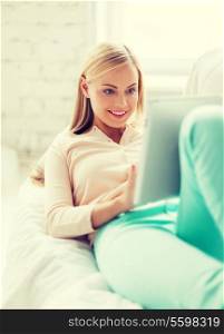 smiling woman lying on the couch with tablet pc