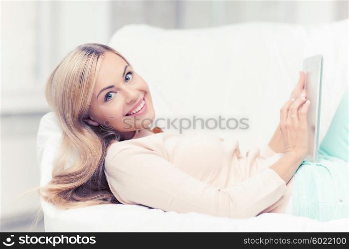 smiling woman lying on the couch with tablet pc. woman with tablet pc