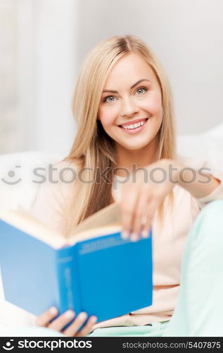 smiling woman lying on the sofa and reading book