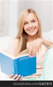 smiling woman lying on the sofa and reading book
