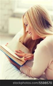 smiling woman lying on the sofa and reading book