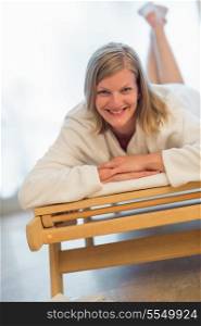 Smiling woman lying on wooden bed at beauty spa
