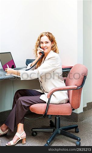Smiling woman on telephone at office desk
