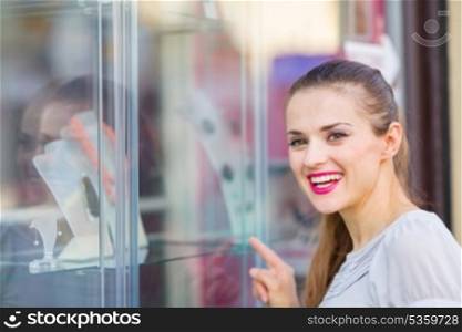 Smiling woman pointing on showcase