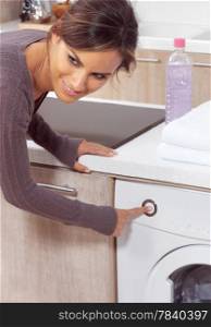 smiling woman pressing a button on her washing machine