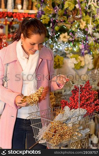 Smiling woman putting Xmas decorations to shopping basket