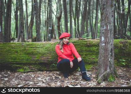 Smiling woman reclining on a mossy tree trunk in the middle of the forest looking at the camera.