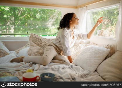 Smiling woman relax in bed, c&ing in a trailer. Couple travels on van, romantic vacations on motorhome, c&er leisures in c&ing-car. Smiling woman relax in bed, c&ing in a trailer