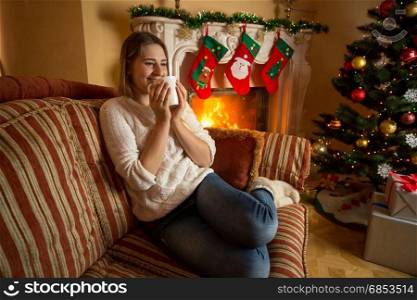 Smiling woman relaxing at fireplace and drinking tea